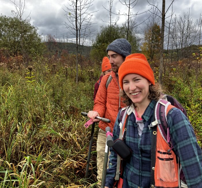 Woman from Vermont Association of Wetland Scientists smiling doing fieldwork in a wetland