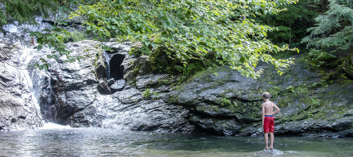 Boy standing in Vermont swimming hole by Jay Ericson