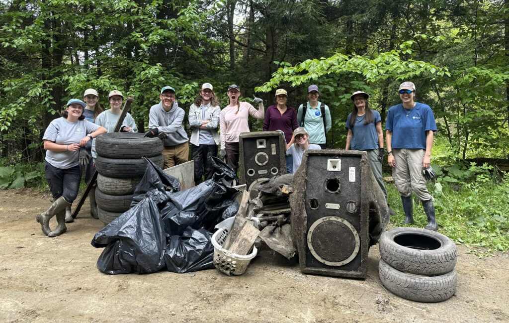 AmeriCorps members and volunteers stand beside bags of collected trash during the Kingsbury Branch River Cleanup, celebrating their efforts to help keep the river and surrounding habitat clean.