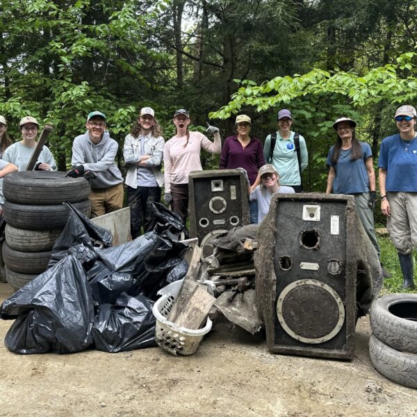 AmeriCorps members and volunteers stand beside bags of collected trash during the Kingsbury Branch River Cleanup, celebrating their efforts to help keep the river and surrounding habitat clean.