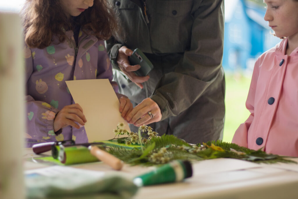Close-up of a mother helping her daughter apply ink to a Gelli plate during the monoprinting workshop.